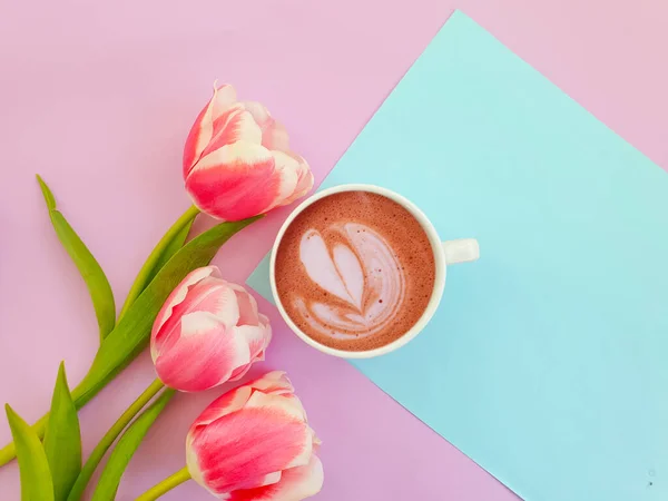 cup of coffee. tulip flower on colored background