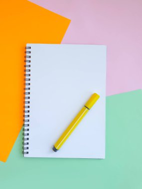 Renkli kağıdın arkaplanındaki keçeli kalem, defter