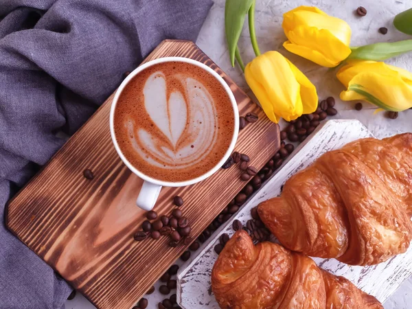 coffee, croissant, tulip flower on concrete background