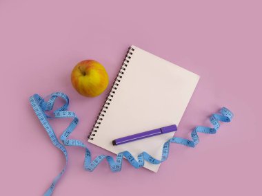 defter, mezura, renkli arkaplanda elma