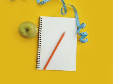 defter, mezura, renkli arkaplanda elma