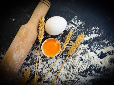 rolling pin, egg, bread ear on concrete background