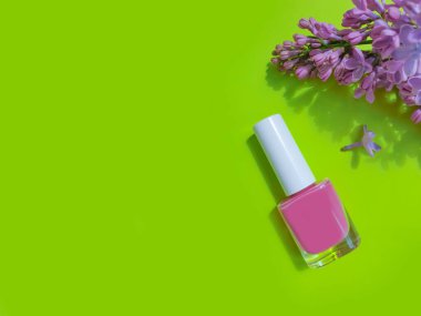 Renkli arkaplan çiçekli leylak renginde oje şişesi.