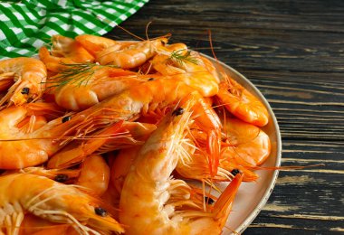 Ahşap zemin üzerinde bir tabakta kaynamış karides.