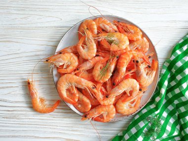 Ahşap zemin üzerinde bir tabakta kaynamış karides.