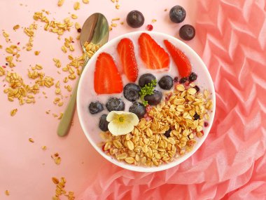 Yoğurt, granola, çilek, renkli bir arka planda yabanmersini.