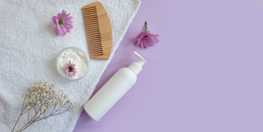 Şampuan, ahşap taraklı çiçek, renkli bir arka plan.