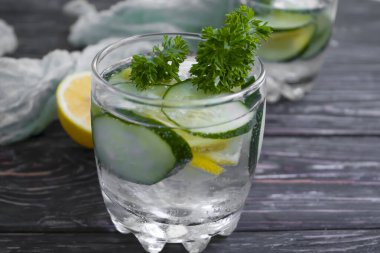 Bir bardak su limonu, salatalık, ahşap arka planda maydanoz.