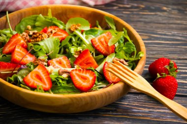 Çilekli salata, ahşap arka planda fındık.