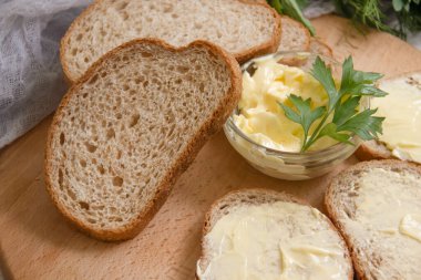 Tahta arka planda tereyağı, ekmek, maydanoz