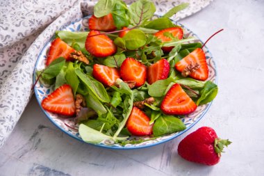 yeşil marul yaprakları, çilekler, tabakta fındıklar