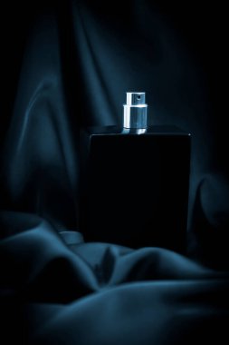 İpek arka planda bir şişe parfüm.