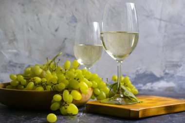 Beton zeminde bir bardak beyaz şarap üzümü.