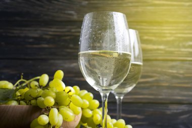 Beton zeminde bir bardak beyaz şarap üzümü.