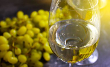 Beton zeminde bir bardak beyaz şarap üzümü.