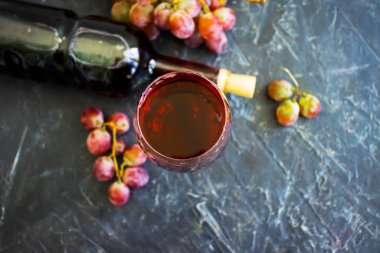 Kırmızı şarap kadehi, beton zeminde taze üzümler.