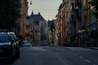 Bir şehir manzarası Stockholm Kungsholmen 'deki binalarla dolu uzun bir caddeyi, yan tarafa park edilmiş arabaları ve bir trafik ışığını yakalıyor, derinlik hissi yaratıyor..