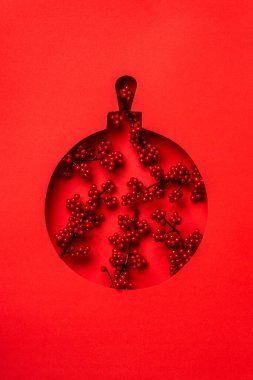 Kırmızı arkaplanda kırmızı böğürtlenli Noel topu..