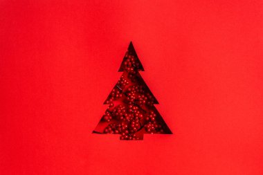 Kırmızı arkaplanda kırmızı böğürtlenli Noel ağacı kesimi.