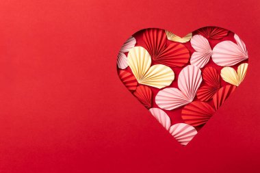 Kırmızıyla, pembeyle ve sarı pervanelerle dolu parlak kırmızı arka planda kalp şeklinde bir kesit..