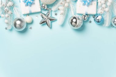 Gümüş süsler, beyaz hediyeler ve açık mavi arkaplan boyunca düzenlenmiş şenlikli süsler..