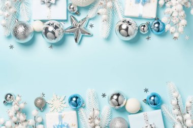 Gümüş süsler, beyaz hediyeler ve açık mavi arkaplan boyunca düzenlenmiş şenlikli süsler..