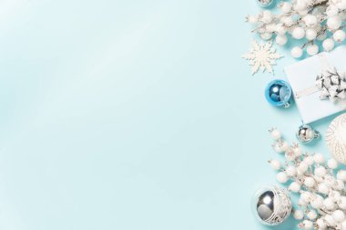 Gümüş süsler, beyaz hediyeler ve açık mavi arkaplan boyunca düzenlenmiş şenlikli süsler..