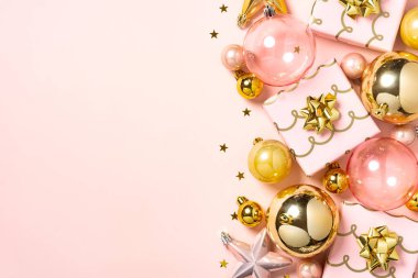 Pembe ve altın Noel süsleri, fiyonklar ve yumuşak pastel arka planda küçük hediyeler..