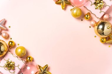 Pembe ve altın rengi Noel süsleri yumuşak bir pastel arka planda dizilmiş..