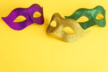 Parlak sarı arka planda renkli karnaval maskeleri.