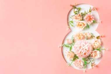 Güllerden ve narin çiçeklerden yapılmış sekiz çiçek figürü. Yumuşak pembe arka plan. 8 Mart Sembolü.