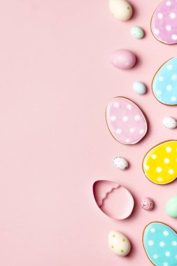 Renkli Paskalya yumurtaları ve dekore edilmiş kurabiyeler fotokopi alanı olan yumuşak pembe bir arka planda..