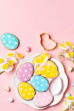 Renkli Paskalya yumurtaları ve dekore edilmiş kurabiyeler fotokopi alanı olan yumuşak pembe bir arka planda..