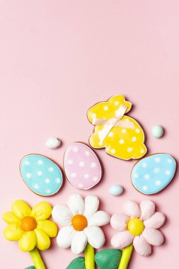 Renkli Paskalya yumurtaları ve dekore edilmiş kurabiyeler fotokopi alanı olan yumuşak pembe bir arka planda..