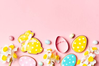 Renkli Paskalya yumurtaları ve dekore edilmiş kurabiyeler fotokopi alanı olan yumuşak pembe bir arka planda..