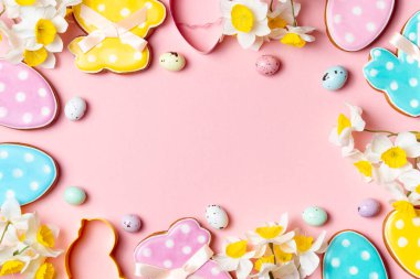 Renkli Paskalya yumurtaları ve dekore edilmiş kurabiyeler fotokopi alanı olan yumuşak pembe bir arka planda..