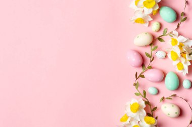 Renkli Paskalya yumurtaları ve dekore edilmiş kurabiyeler fotokopi alanı olan yumuşak pembe bir arka planda..