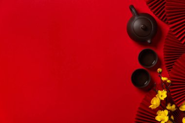 Dekoratif yelpazeli geleneksel Çin çayı seti ve kırmızı arka planda fotokopi alanı olan çiçekler..