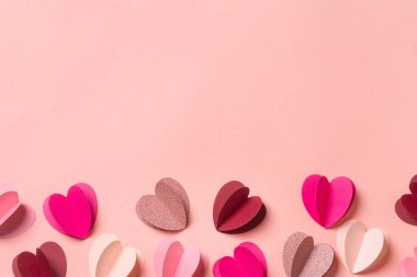 Yumuşak pembe arka planda kağıt kalpler. Fotokopi alanı olan en az romantik kompozisyon. Sevgililer Günü konsepti.