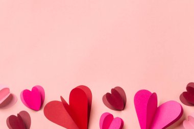 Yumuşak pembe arka planda kağıt kalpler. Fotokopi alanı olan en az romantik kompozisyon. Sevgililer Günü konsepti.