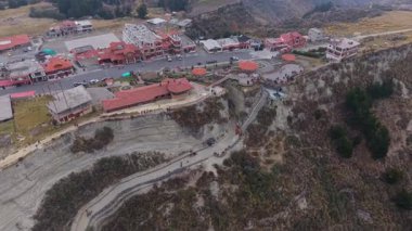 And kasabası Quilotoa dramatik bir şekilde tünemiş, sarmal yollar, sarp dağlık araziye sıkıca tutunarak binaların içinden geçiyor..