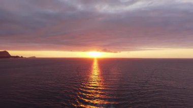 Kıyıya yakın seyreden lüks bir yat, altın gün batımında sakin sularda süzülüyor, pürüzsüz okyanus yüzeyine yansıyan ılık renkler..