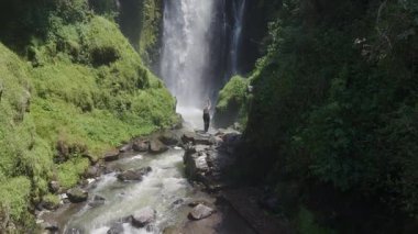 Verdant yağmur ormanları, güçlü şelaleleri çerçeveliyor. Ekvador manzarasında çağlayarak ilerliyor. Sarışın kadın gezgin, el değmemiş vahşi doğaya havadan bakıyor..