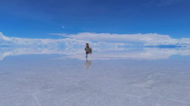 Bolivya 'daki geniş Salar de Uyuni tuz düzlüklerinde koşan bir kadın manzaranın huzurlu güzelliğini yakalıyor..