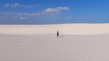 Tek bir kişi, Socotra Adası 'ndaki açık mavi gökyüzünün altında engin kum tepelerini aşar..