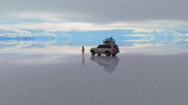 Bolivias Salar de Uyuni 'nin yansıtıcı yüzeyinde yürüyen bir kadın, dünyanın en büyük tuz tabakasının dingin güzelliğini yakalıyor..