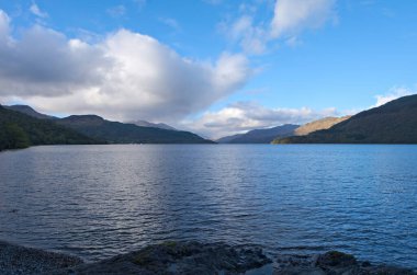 Ben Vorlich 'e ve Firkin Point' ten uzak Tyndrum tepelerine akşam manzarası, Lomond Gölü 'nün batı kıyısındaki A82' ye bakış açısı, OS haritası hakemi NN 338 007, Argyll ve Bute, İskoçya.