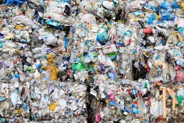 Endüstriyel geri dönüşüm tesisinde istiflenmiş plastik kırıntılarından oluşan büyük bir koleksiyonun havadan görünüşü