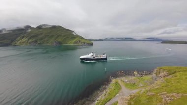Alaska, Unalaska 'daki fabrika trol teknesinin ve dağ kıyısının havadan görüntüsü. Bering Denizi, Alaska, ABD 'de ticari balıkçılık. Hollanda Limanı 'ndaki berrak sularda ilerleyen balıkçı teknesi