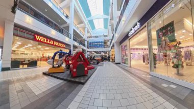 Anchorage, Alaska 'da kapalı alışveriş merkezinde yürüyüş. Videoda Wells Fargo Bank, çocuk gezileri ve çeşitli renkli butikler ve dükkanlar görülüyor. Anchorage 28.11.25